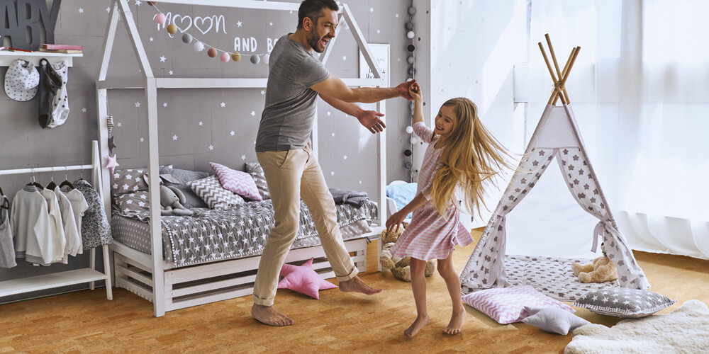 Father and daughter dancing on cork flooring