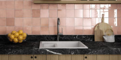 Glossy square peach tile backsplash and black marble countertops in kitchen