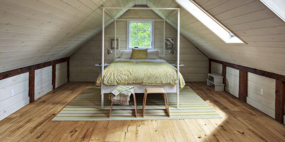queen bed with a white bed frame in a loft with wooden floors