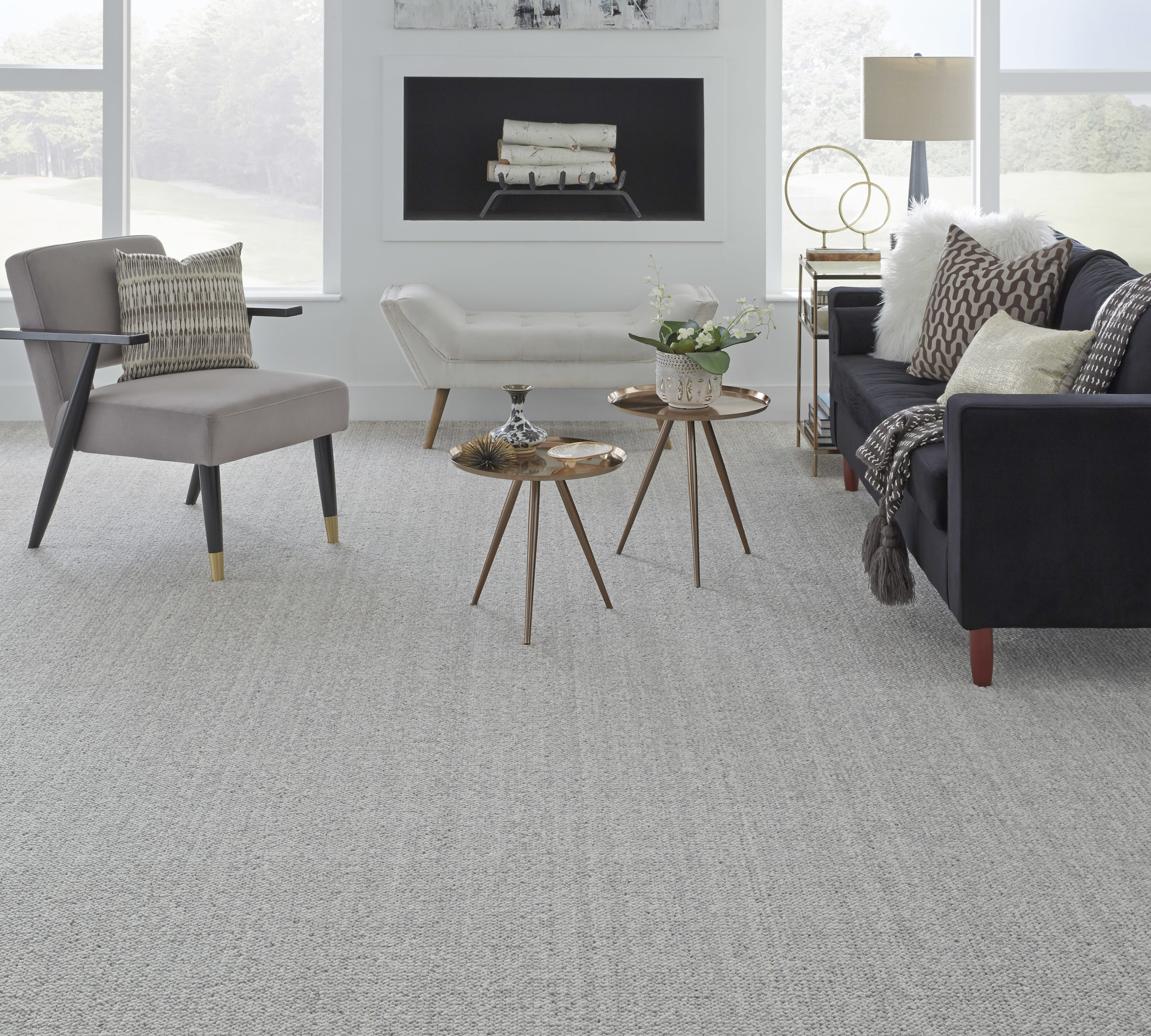 Grey wool carpet in a modern furnished living room with a white fireplace.