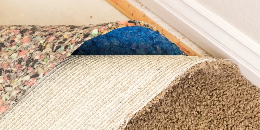 Pulled back carpet and padding on the floor of a house